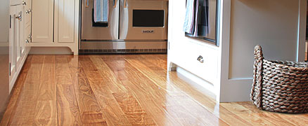 Wide plank flooring in a kitchen with white cabinets and stainless steel appliances