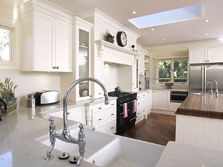 French country kitchen design - white cabinets in combination with stone counters, porcelain sink and stainless steel appliances. The floor and the counter of the island are made of wood