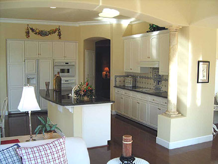An open kitchen design with island in the center. The design offers a seamless extension into the living room