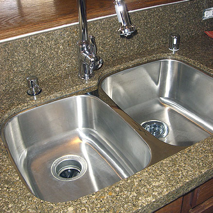 Undermount double bowl stainless steel kitchen sink fitted to the bottom of a granite countertop
