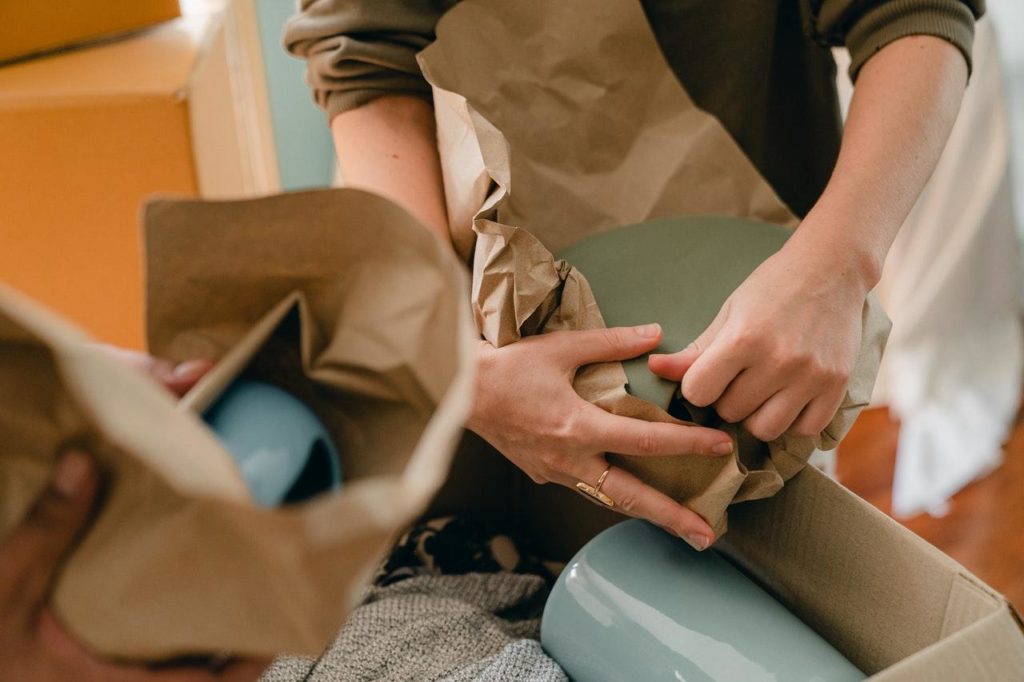 Person packing ceramic tableware in parchment