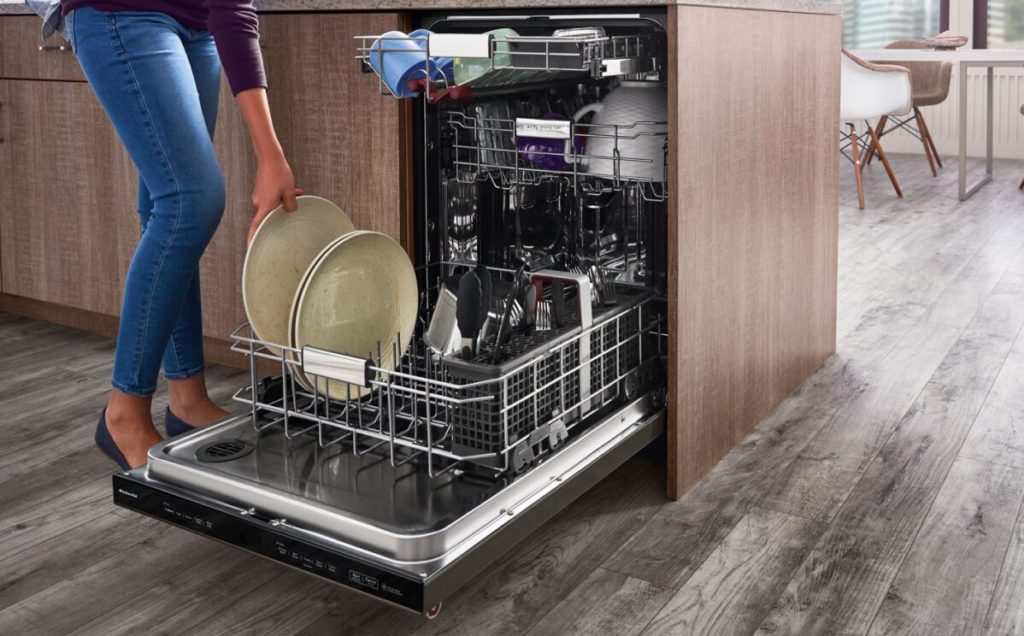 A woman putting dirty dishes in a dishwasher.