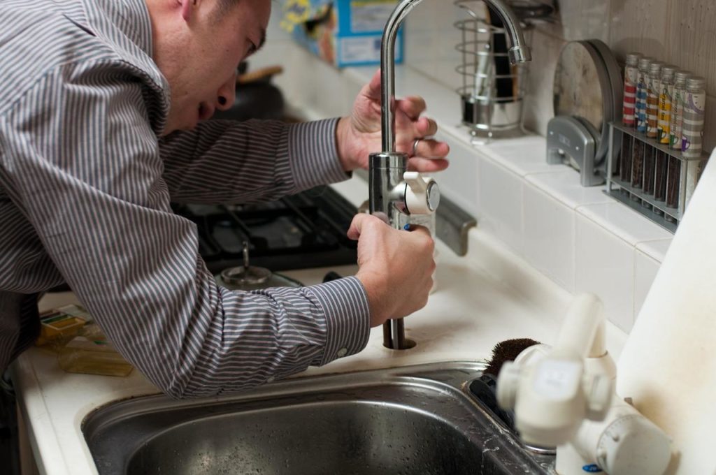 A man installs a drop-in kitchen sink and faucet.