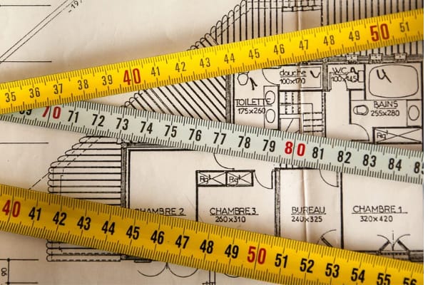 Several tape-measures over home plans.